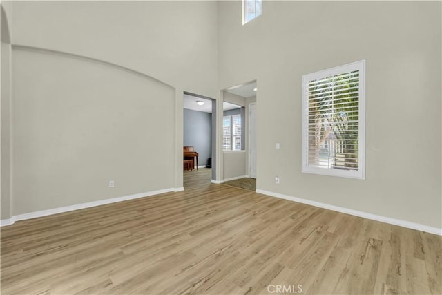 interior space with baseboards, light wood finished floors, and a healthy amount of sunlight