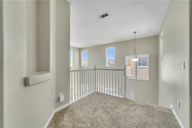 hall with carpet floors, baseboards, and visible vents