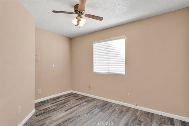 empty room with a textured ceiling, wood finished floors, and baseboards