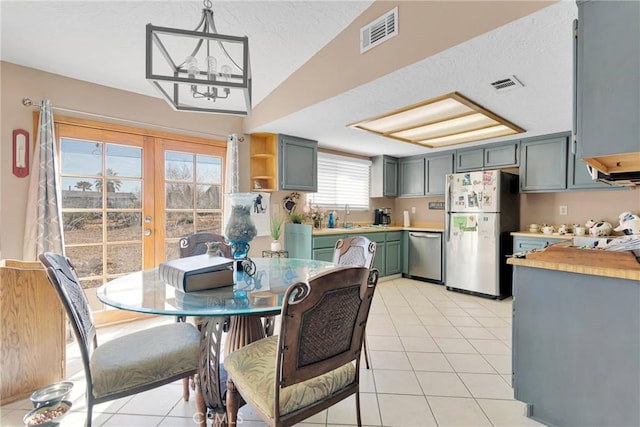 dining space featuring light tile patterned floors, french doors, vaulted ceiling, and visible vents