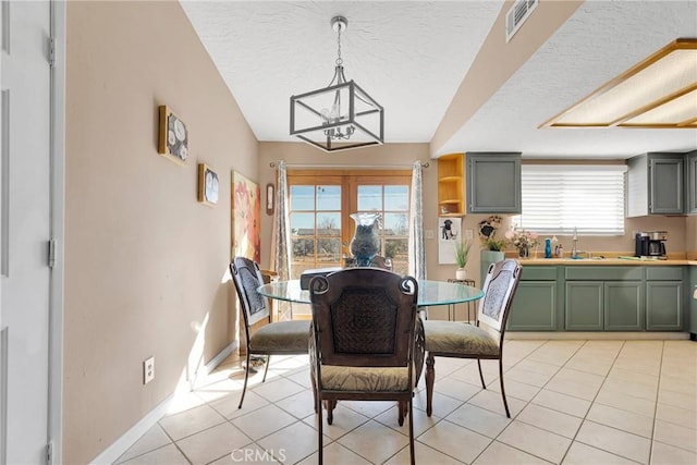 dining room with a textured ceiling, light tile patterned flooring, a notable chandelier, visible vents, and baseboards