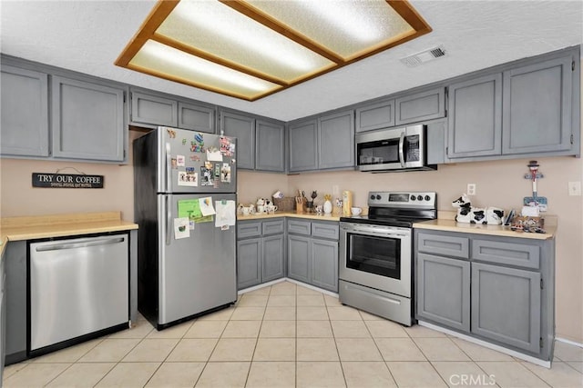 kitchen featuring stainless steel appliances, gray cabinets, light countertops, and visible vents