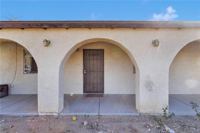 property entrance with heating fuel and stucco siding