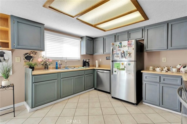 kitchen with light tile patterned flooring, a sink, light countertops, appliances with stainless steel finishes, and open shelves