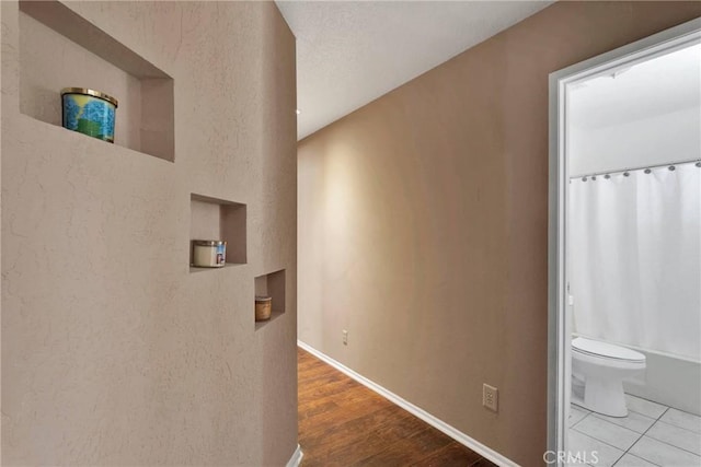 hallway with baseboards and wood finished floors