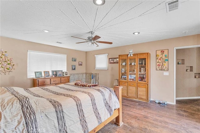 bedroom featuring baseboards, visible vents, wood finished floors, and recessed lighting