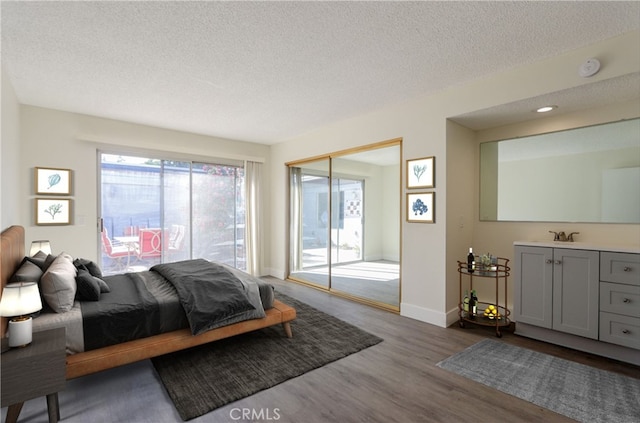 bedroom featuring dark wood-type flooring, a sink, a textured ceiling, and baseboards