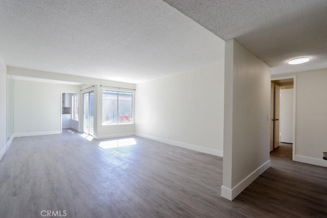 empty room with dark wood-style floors, a textured ceiling, and baseboards