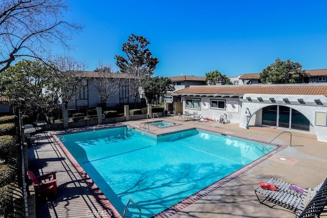 community pool featuring a patio area, fence, and a community hot tub