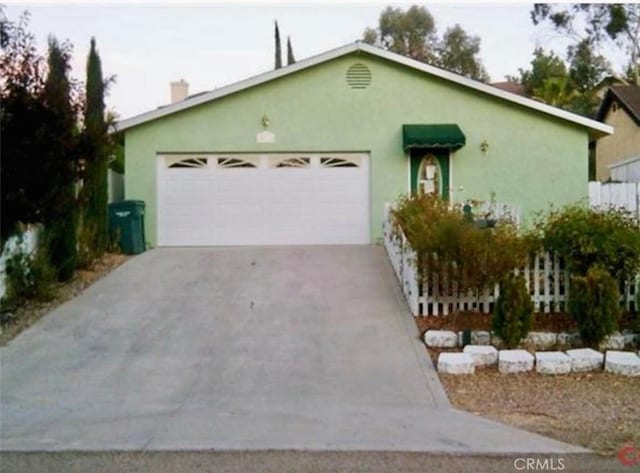 ranch-style home with a garage, concrete driveway, and stucco siding