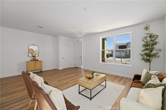 living area with baseboards, visible vents, and light wood finished floors