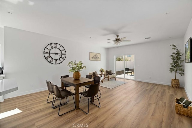 dining room featuring light wood-style floors, visible vents, baseboards, and a ceiling fan