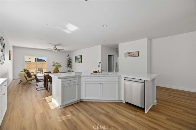 kitchen featuring light countertops, stainless steel dishwasher, light wood-style floors, white cabinets, and a sink