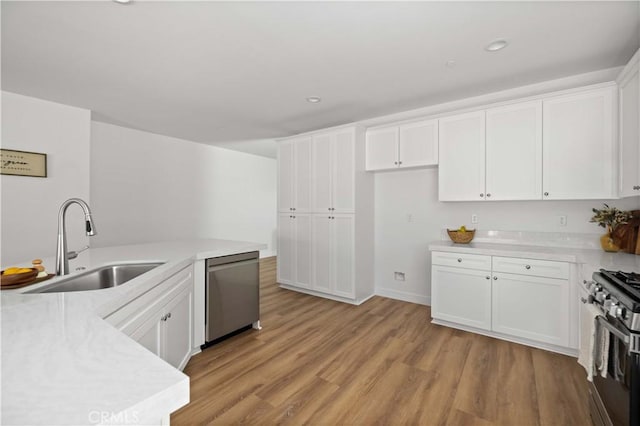 kitchen with light countertops, appliances with stainless steel finishes, a sink, and white cabinetry