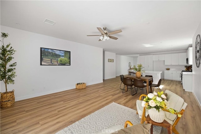 dining area featuring visible vents, ceiling fan, light wood-style flooring, and baseboards