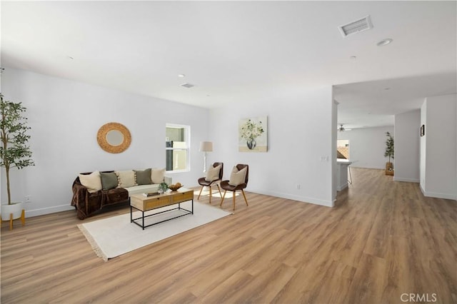 living area with light wood-style floors, baseboards, and visible vents