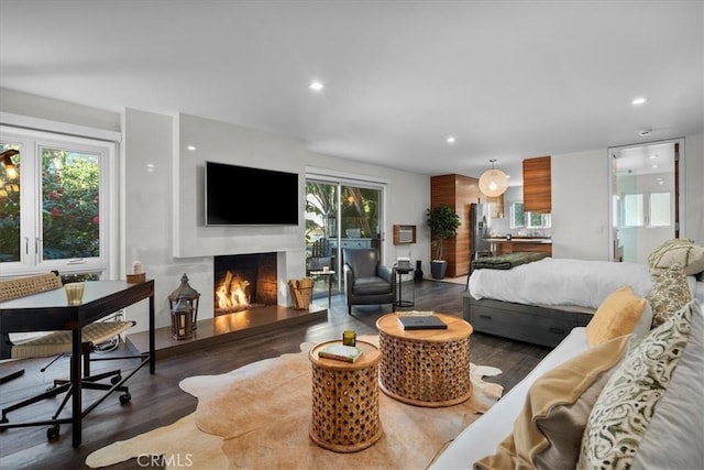 bedroom featuring a lit fireplace, access to outside, wood finished floors, and recessed lighting