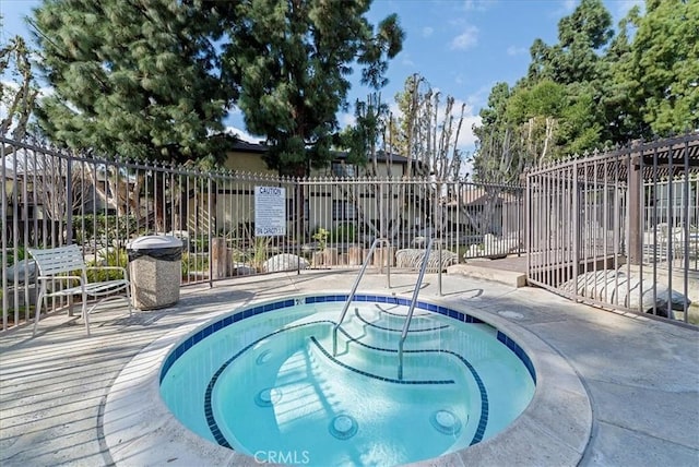 view of swimming pool featuring fence and a hot tub