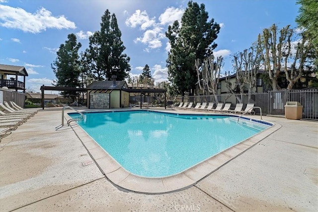 pool with a patio area, fence, and an outdoor structure