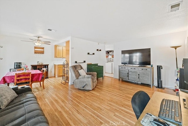 living area with light wood-type flooring, visible vents, and ceiling fan