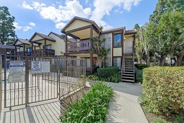 view of front facade featuring fence, stairway, and stucco siding