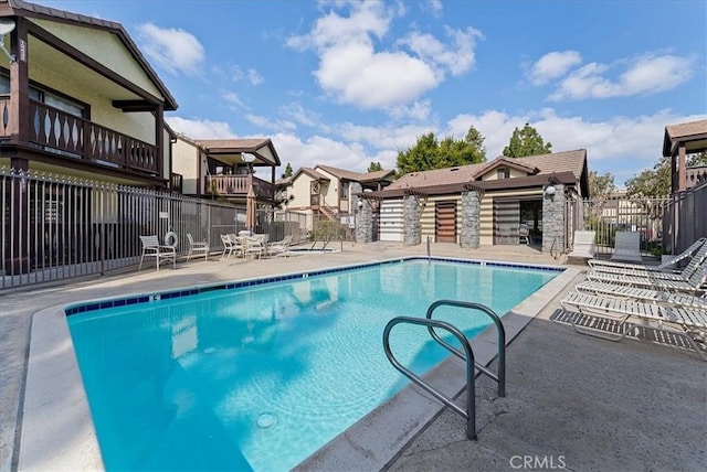 pool with a patio area and fence