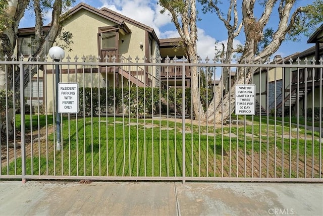 view of gate with stairway and a lawn