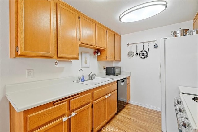 kitchen featuring appliances with stainless steel finishes, light countertops, a sink, and light wood finished floors