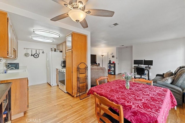 dining area with light wood-style floors, visible vents, and ceiling fan