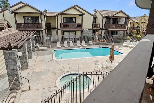 pool featuring a community hot tub, a patio, stairway, and fence