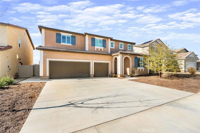 mediterranean / spanish-style house featuring a garage, driveway, a tile roof, and stucco siding