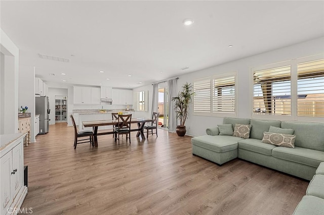 living area with light wood-type flooring, visible vents, and recessed lighting