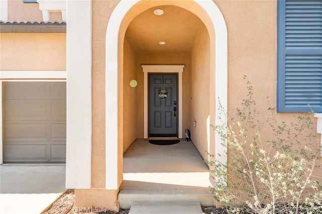 property entrance featuring a garage and stucco siding