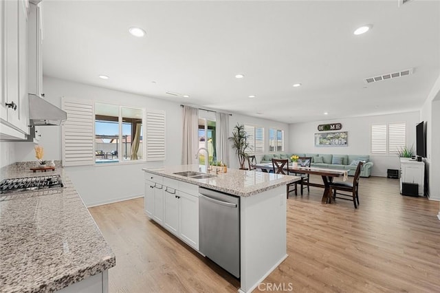 kitchen featuring light stone counters, a sink, white cabinetry, open floor plan, and appliances with stainless steel finishes