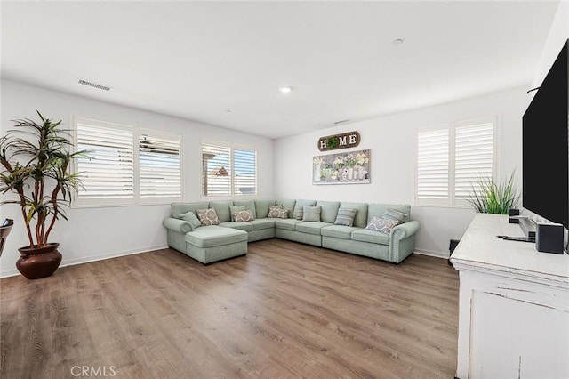 living area featuring light wood-style flooring, visible vents, and baseboards