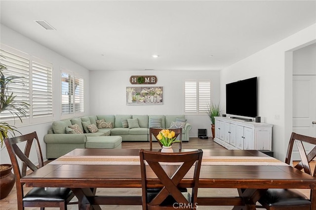 living room featuring visible vents, light wood-style flooring, and a wealth of natural light