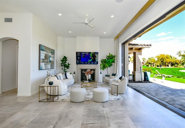 living room featuring baseboards, visible vents, arched walkways, a ceiling fan, and recessed lighting