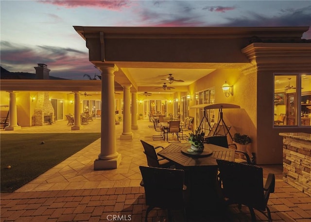 patio terrace at dusk featuring ceiling fan, outdoor dining area, and an outdoor living space