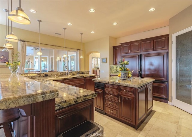 kitchen with visible vents, arched walkways, a spacious island, a sink, and recessed lighting