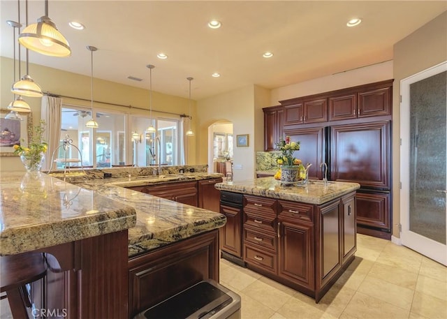 37305 Calle De Lobo, Murrieta, CA 92562 - kitchen with a spacious island, arched walkways, recessed lighting, decorative light fixtures, and light stone counters