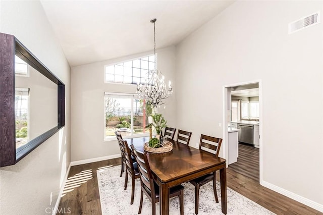 dining area with dark wood-style floors, a healthy amount of sunlight, visible vents, and a notable chandelier