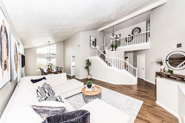 living room featuring baseboards, a chandelier, wood finished floors, stairs, and high vaulted ceiling