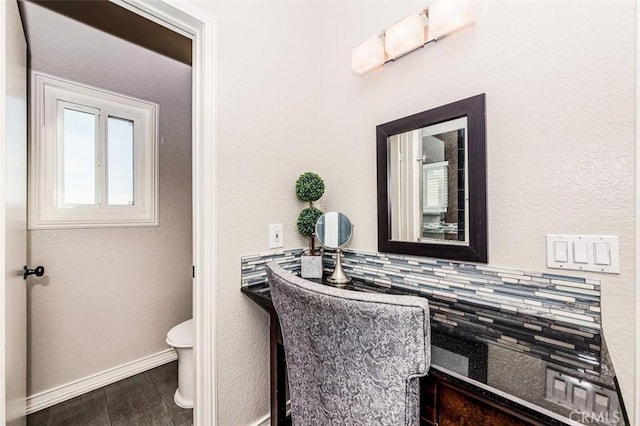 half bath featuring wood finished floors, toilet, and baseboards