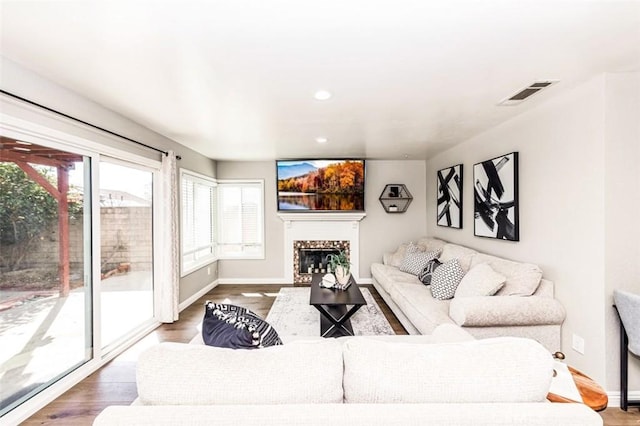 living room with baseboards, a fireplace, visible vents, and wood finished floors