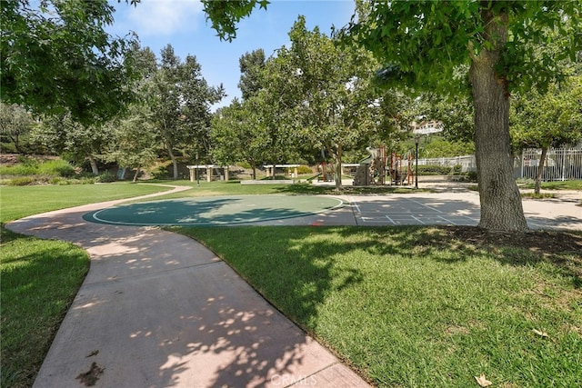 view of community featuring playground community, a lawn, and fence