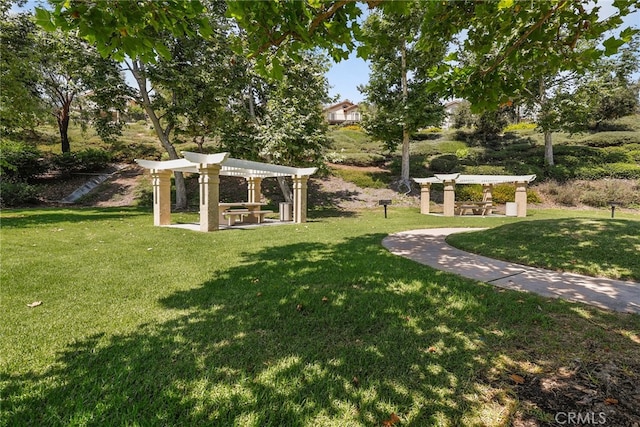 view of community featuring a pergola and a yard