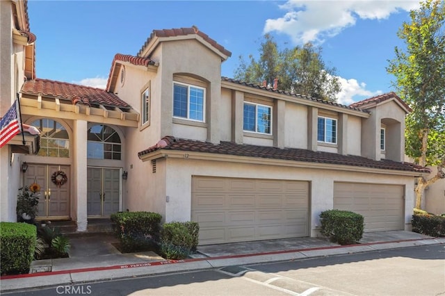 mediterranean / spanish home featuring an attached garage, concrete driveway, and stucco siding