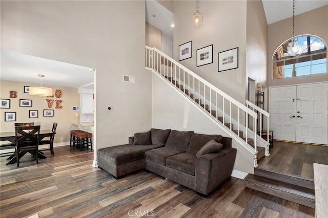 living room featuring baseboards, visible vents, stairway, wood finished floors, and a high ceiling