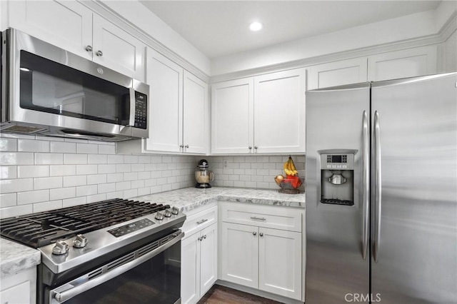 kitchen featuring appliances with stainless steel finishes, white cabinets, backsplash, and light stone countertops