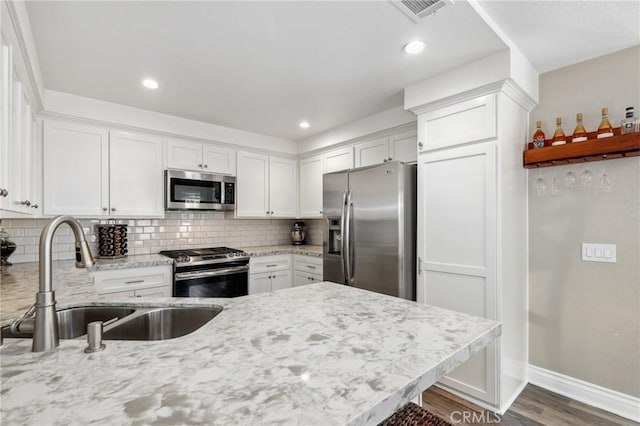 kitchen with light stone countertops, white cabinetry, appliances with stainless steel finishes, and a sink